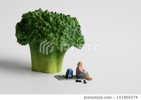 Miniature woman resting under green broccoli Miniature woman resting under green broccoli 141909374