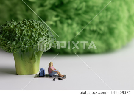 Miniature woman resting under green broccoli 141909375