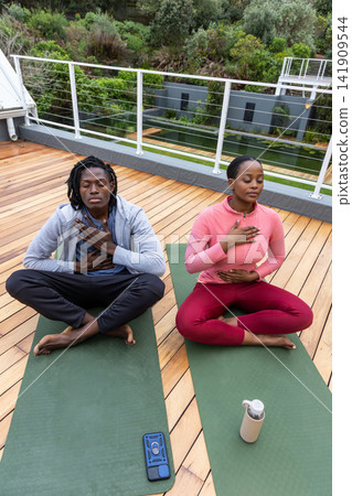 African American pair wearing hoodie, top breathing on green mats on roof, phone left, bottle right African American pair wearing hoodie, top breathing on green mats on roof, phone left, bottle right 141909544