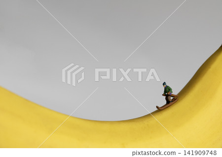 Miniature man skiing on a yellow ripe banana Miniature man skiing on a yellow ripe banana 141909748