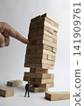 Precarious wooden blocks and miniature businessman 141909761