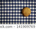 A oatmeal cookie on a blue and white checkered tablecloth 141909769
