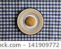 A oatmeal cookie on a blue and white checkered tablecloth 141909772