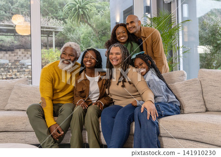 African American family smiling and posing on sectional sofa at home near windows African American family smiling and posing on sectional sofa at home near windows 141910230