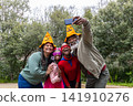 African American family taking selfie on paved path in park, wearing pumpkin hats, tutu, sunglasses 141910276