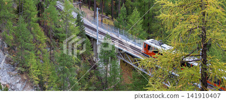 Switzerland, Red Gornergrat train crossing near Zermatt Swiss Alps Switzerland, Red Gornergrat train crossing near Zermatt Swiss Alps 141910407