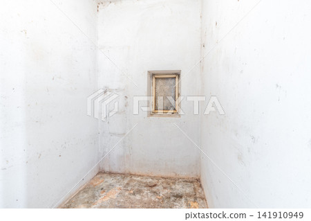 Empty dilapidated room with grimy white walls and small window Empty dilapidated room with grimy white walls and small window 141910949