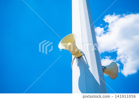 Megaphone loudspeaker mounted on metal pole against clear blue sky, public announcement and communication concept Megaphone loudspeaker mounted on metal pole against clear blue sky, public announcement and communication concept 141911056