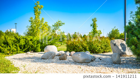 Large smooth boulders and white gravel stones decorative landscaping in summer city park, zen garden design concept Large smooth boulders and white gravel stones decorative landscaping in summer city park, zen garden design concept 141911211