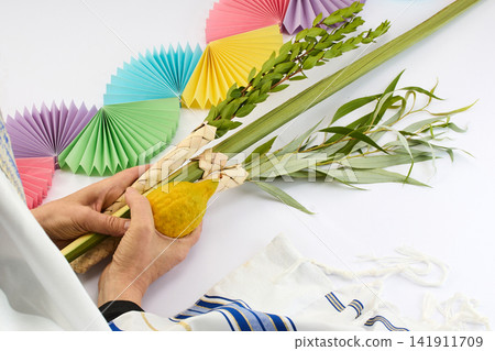 Hands holding sukkot four species with tallit and decorations Hands holding sukkot four species with tallit and decorations 141911709