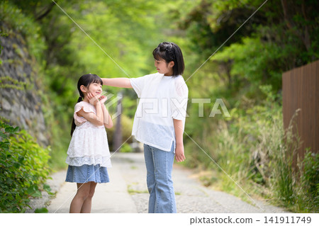 The older sister gently strokes the younger sister's head. The older sister gently strokes the younger sister's head. 141911749