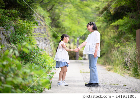 The sisters walk side by side, holding hands. The sisters walk side by side, holding hands. 141911803