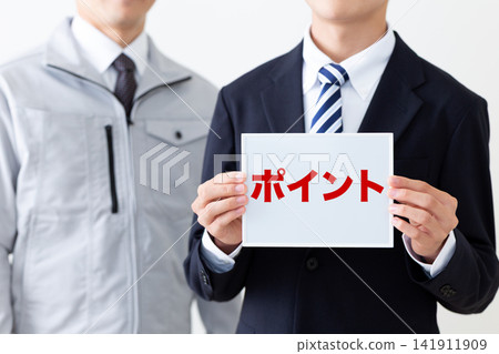 A young businessman in a business suit holding a whiteboard with points on it. A young businessman in a business suit holding a whiteboard with points on it. 141911909