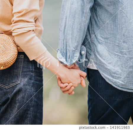 An intimate scene of a couple holding hands outdoors. An intimate scene of a couple holding hands outdoors. 141911983