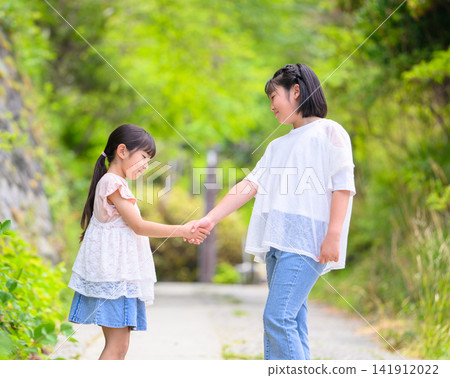 Two close sisters walking hand in hand. Two close sisters walking hand in hand. 141912022