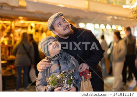 Man with son stands in middle of shopping area decorated for New Year holidays Man with son stands in middle of shopping area decorated for New Year holidays 141912117
