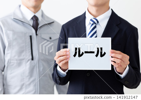 身穿西裝的年輕商人,手持一塊寫著規則的白板。 身穿西裝的年輕商人,手持一塊寫著規則的白板。 141912147