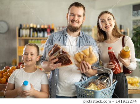 Young family with little son holding products in supermarket Young family with little son holding products in supermarket 141912274