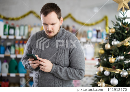 Male buyer in household chemicals store types message Male buyer in household chemicals store types message 141912370
