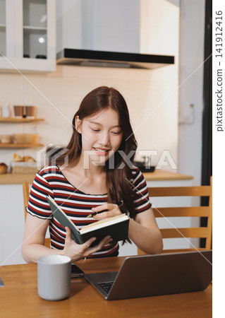 Asian woman using computer remote for business studying, watching online virtual webinar training meeting, video call. asian business woman talking on laptop in home office. Banner, copy space Asian woman using computer remote for business studying, watching online virtual webinar training meeting, video call. asian business woman talking on laptop in home office. Banner, copy space 141912416