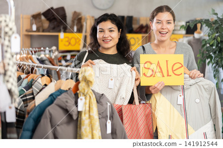 Two women on sale with shoppers and a poster Two women on sale with shoppers and a poster 141912544