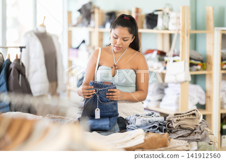 Undetermined young girl choosing jeans pantaloons in clothing store Undetermined young girl choosing jeans pantaloons in clothing store 141912560