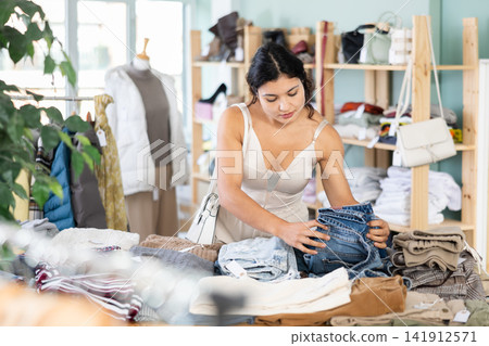 Young woman choosing jeans in clothing store Young woman choosing jeans in clothing store 141912571