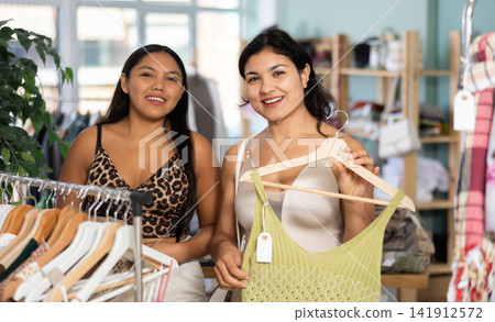 Two girlfriends chooses dresses or o tops for the summer period in fashionable clothing store Two girlfriends chooses dresses or o tops for the summer period in fashionable clothing store 141912572