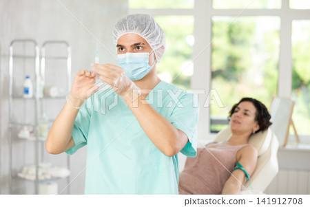 Doctor anesthetist checks the syringe before injection to patient Doctor anesthetist checks the syringe before injection to patient 141912708