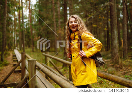 Hiker woman with a backpack hiking on a wooden path in a swamp forest. Active lifestyle Hiker woman with a backpack hiking on a wooden path in a swamp forest. Active lifestyle 141913045