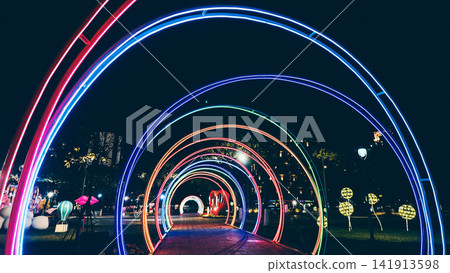 colorful neon light tunnel with glowing rainbow arches and futuristic night perspective, illuminated LED walkway with vibrant festive decoration and abstract cyberpunk atmosphere background colorful neon light tunnel with glowing rainbow arches and futuristic night perspective, illuminated LED walkway with vibrant festive decoration and abstract cyberpunk atmosphere background 141913598