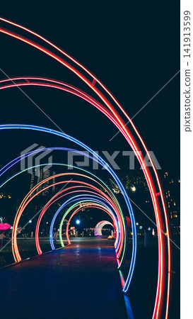 colorful neon light tunnel with glowing rainbow arches and futuristic night perspective, illuminated LED walkway with vibrant festive decoration and abstract cyberpunk atmosphere background colorful neon light tunnel with glowing rainbow arches and futuristic night perspective, illuminated LED walkway with vibrant festive decoration and abstract cyberpunk atmosphere background 141913599