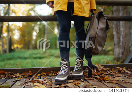 Woman's legs in boots in autumn foliage. Leaf fall. Lifestyle concept. 141913874