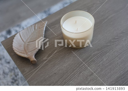 Neutral Home Decor with Candle and Wooden Leaf Ornament on Coffee Table Neutral Home Decor with Candle and Wooden Leaf Ornament on Coffee Table 141913893