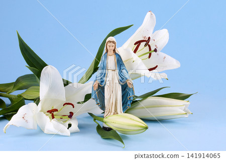 Virgin mary statue with white lilies on blue background Virgin mary statue with white lilies on blue background 141914065