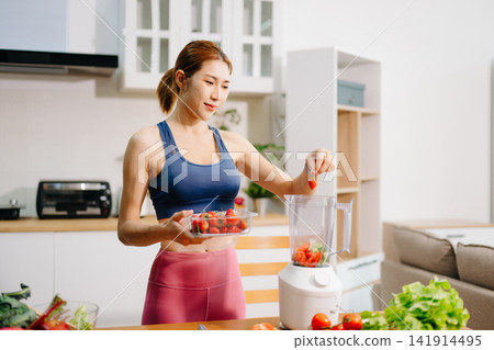 Fitness woman preparing fresh vegetable smoothie in blender at home kitchen, healthy lifestyle concept with organic ingredients, nutrition, diet, wellness Fitness woman preparing fresh vegetable smoothie in blender at home kitchen, healthy lifestyle concept with organic ingredients, nutrition, diet, wellness 141914495