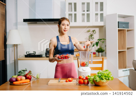 Fitness woman preparing fresh fruit smoothie in blender at home kitchen, healthy lifestyle concept with organic ingredients, nutrition, diet, wellness Fitness woman preparing fresh fruit smoothie in blender at home kitchen, healthy lifestyle concept with organic ingredients, nutrition, diet, wellness 141914502