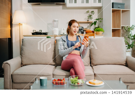 Young woman enjoying healthy meal at home after workout, clean eating lifestyle concept, fitness diet, wellness routine in cozy modern living space. Young woman enjoying healthy meal at home after workout, clean eating lifestyle concept, fitness diet, wellness routine in cozy modern living space. 141914539