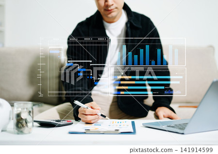 Businessman hand Project manager working and update tasks and Gantt chart scheduling virtual diagram.with smart phone, tablet and laptop in office. Businessman hand Project manager working and update tasks and Gantt chart scheduling virtual diagram.with smart phone, tablet and laptop in office. 141914599