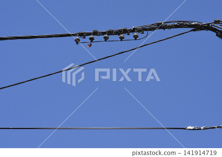 Overhead power cables and electrical connections against a blue sky 141914719