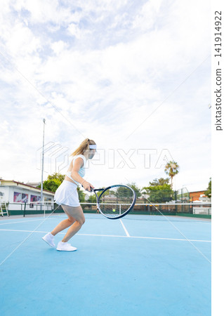 Woman athlete playing tennis on blue court Woman athlete playing tennis on blue court 141914922