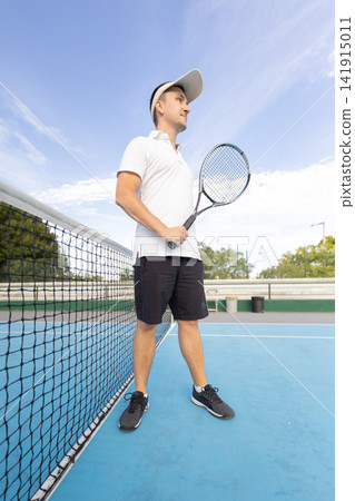 Male tennis player holding racket on court Male tennis player holding racket on court 141915011