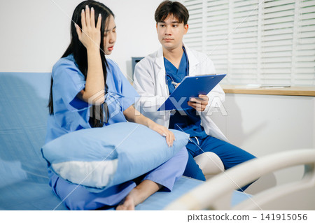 Professional male doctor discussing medical chart with an Asian patient in a hospital bed. Professional male doctor discussing medical chart with an Asian patient in a hospital bed. 141915056