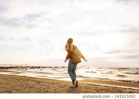 Young woman walking along sea at sunset. Travel, weekend, relax and lifestyle concept. Young woman walking along sea at sunset. Travel, weekend, relax and lifestyle concept. 141915092