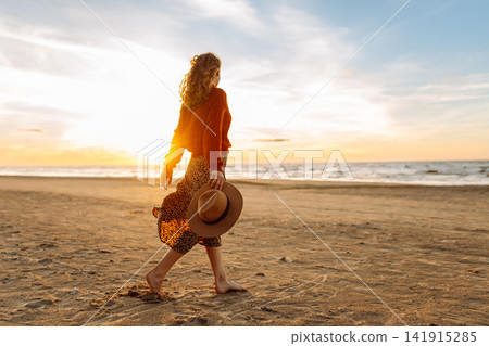 Beautiful woman at windy spring day relaxing on coast. Lady looking at sunset. Travelling, lifestyle Beautiful woman at windy spring day relaxing on coast. Lady looking at sunset. Travelling, lifestyle 141915285