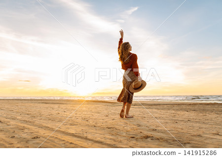 Beautiful woman at windy spring day relaxing on coast. Lady looking at sunset. Travelling, lifestyle Beautiful woman at windy spring day relaxing on coast. Lady looking at sunset. Travelling, lifestyle 141915286