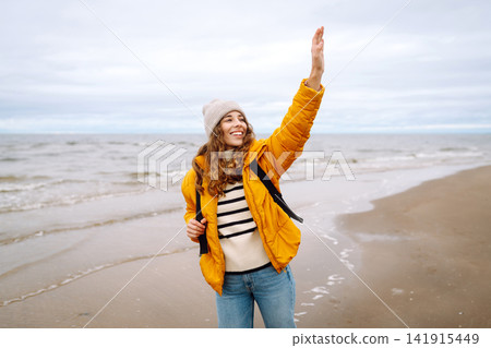 Attractive woman on a windy cold beach. Travel, nature concept. 141915449