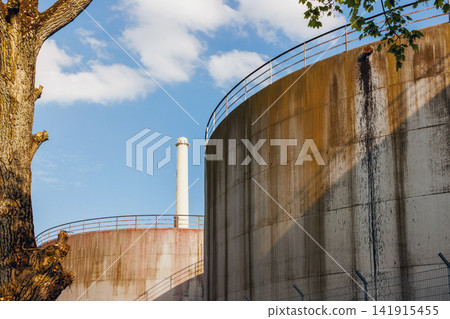 Weathered industrial storage tanks and smokestack at sugar factory in Ochsenfurt Germany. Weathered industrial storage tanks and smokestack at sugar factory in Ochsenfurt Germany. 141915455