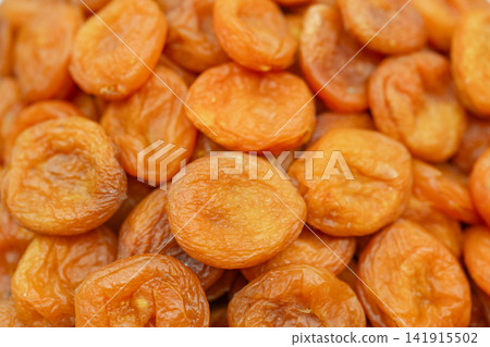 Dried apricots stacked, in close-up view, with dried apricots, from a top-down perspective perspective, with orange, brown accents, and natural and appetizing mood, nearby objects. Dried apricots stacked, in close-up view, with dried apricots, from a top-down perspective perspective, with orange, brown accents, and natural and appetizing mood, nearby objects. 141915502