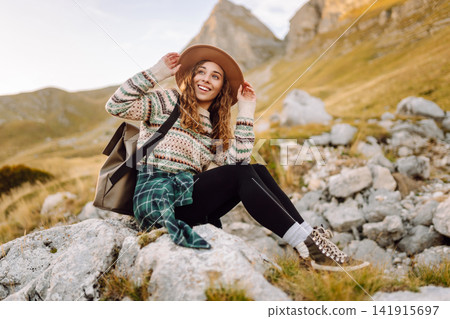 Happy woman stands on rocky terrain, gazing out at breathtaking landscape before her. Lifestyle. Happy woman stands on rocky terrain, gazing out at breathtaking landscape before her. Lifestyle. 141915697